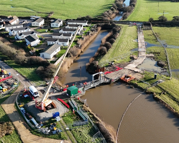 A river with a crane on a bridge.