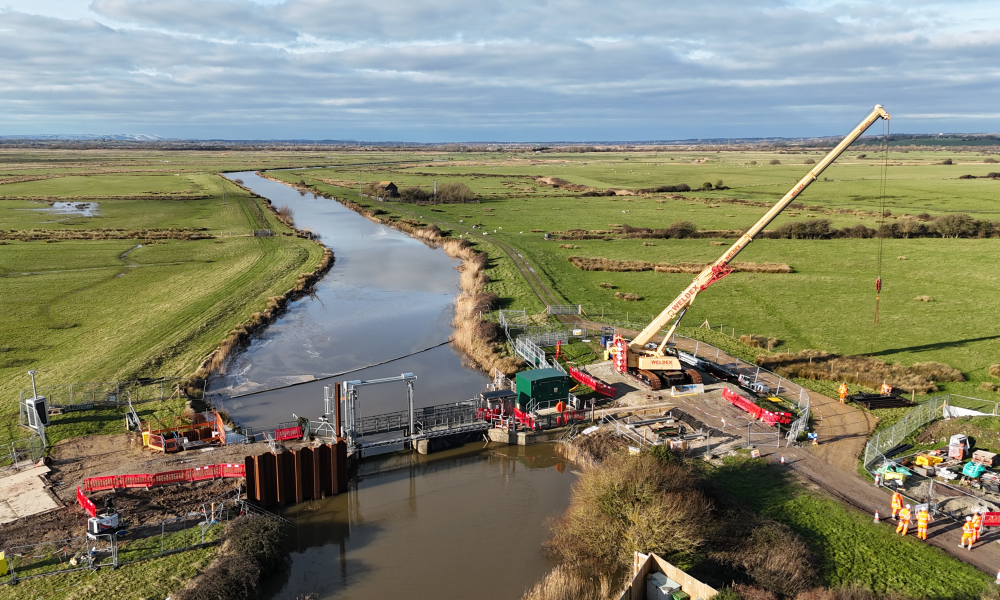 A river with a crane on a bridge.